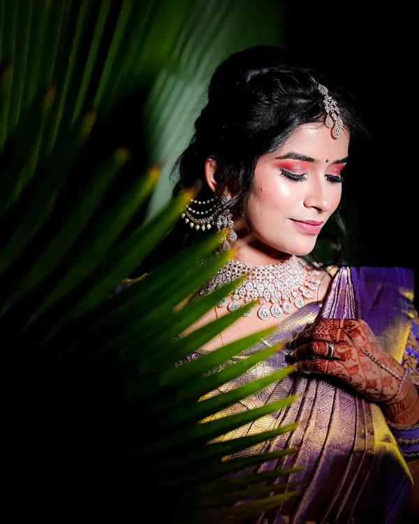 A creative portrait of the bride, her face partially hidden by a palm leaf. We use natural elements to create unique and artistic bridal shots.