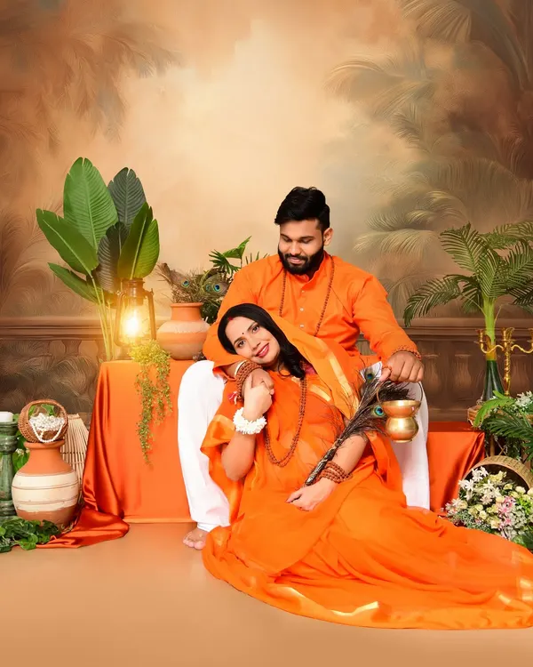 A beautiful couple's portrait from our Ram and Sita inspired maternity shoot. The couple is dressed in traditional orange attire, sharing a tender moment in a setting designed to evoke a classic, epic feel.
