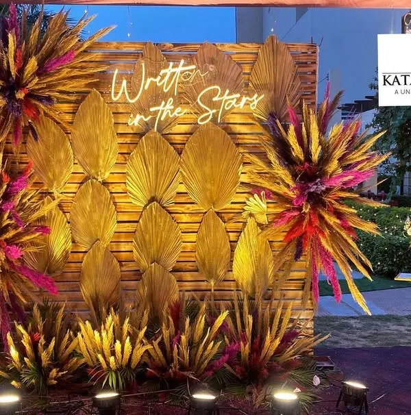 A great photo booth is essential for making memories. For this event, I designed a 'Written in the Stars' backdrop using a wooden wall, golden dried palm leaves, and colorful floral bursts to create a modern and stylish spot for photos.