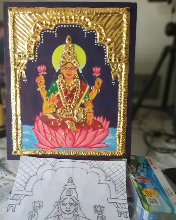A complete Lakshmi Tanjore painting, shown alongside the initial sketch. This piece, featuring the Goddess of Prosperity on a lotus, is crafted with real gold foil and semi-precious stones, ready to bring blessings to your home.