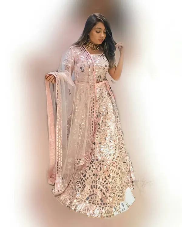 This stunning baby pink lehenga is fully embellished with intricate mirror work, creating a dazzling effect. It's a show-stopping piece perfect for a bride's sangeet or a glamorous wedding guest look.