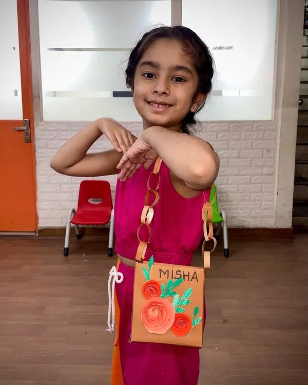 This student is striking a pose with the stylish paper purse she made. This craft project teaches kids about construction, decoration, and creating something functional from simple materials.