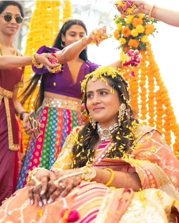 A beautiful moment from a Haldi ceremony. The bride is showered with flowers, and her makeup is kept fresh and minimal to let her natural glow shine through.
