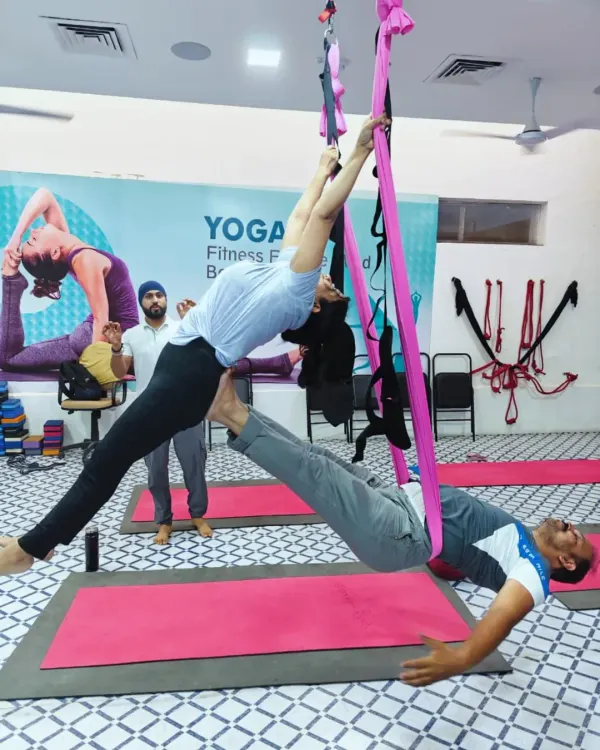 Here I am assisting a student in a partner aerial pose. The hammock provides support, allowing one student to fly while the other acts as a grounding base.