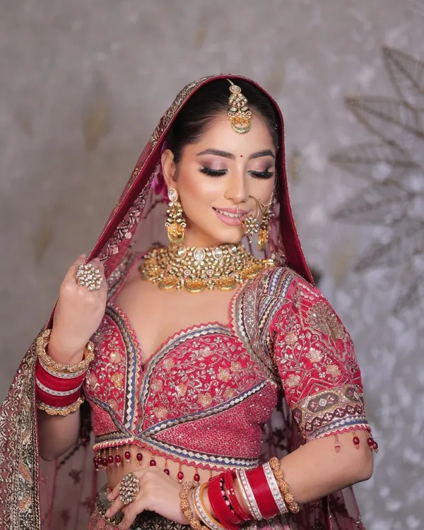 A close-up of this beautiful bride, showcasing the soft glam eye makeup and flawless base that complements her traditional red lehenga. Her smile says it all.
