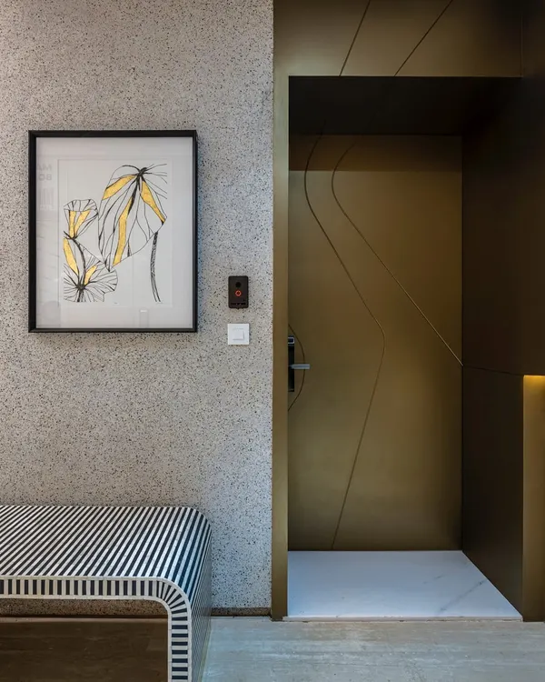 Embrace elegance at the entrance of this Mumbai duplex. A matte gold main door invites with a promise of opulence, while a striking black and white bench sets the stage for the refined luxury that unfolds inside.