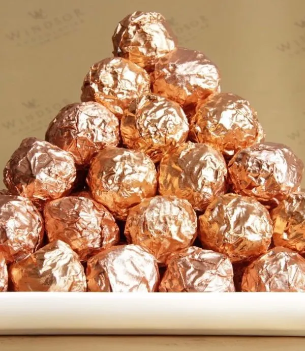 A pyramid of our signature NOCOCHOCO hazelnut truffles. Each one is a sphere of creamy milk chocolate and crunchy wafer surrounding a whole toasted hazelnut, all wrapped in a beautiful rose gold foil.