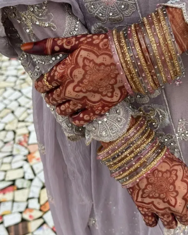 The beautiful result of natural henna. This rich maroon stain on the bride's hands, adorned with bangles, is what I aim for with every design.