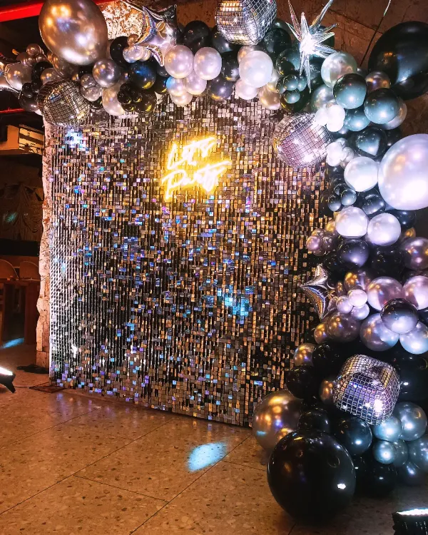 This is one of our favourite setups for a high-energy corporate party. The combination of a shimmer wall, a cool neon sign, and a stylish balloon garland creates a fantastic focal point for any event. 🤩