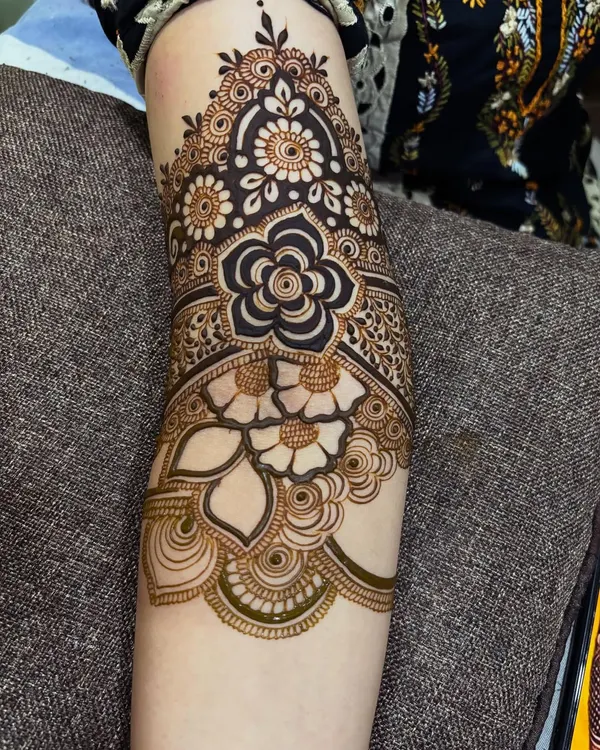This design features a large, bold flower as the centerpiece on the forearm, surrounded by delicate shading and smaller floral details. It's a great example of a modern floral cuff.