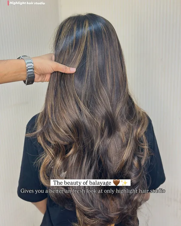 The beauty of balayage. Look at how these hand-painted highlights create a fresh, dimensional look on this client's long hair, styled with soft waves.