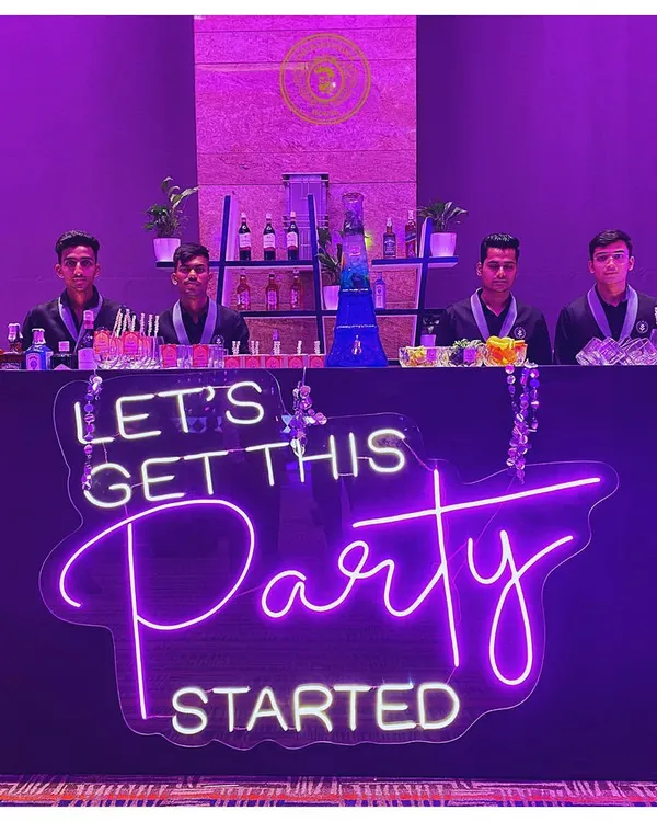 We set the mood for the night. This custom neon sign, "Let's Get This Party Started," makes it clear where the fun is at, with our professional team ready to serve.