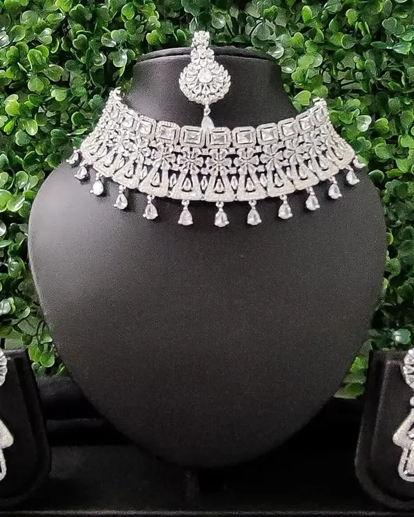 For the modern bride who loves to sparkle, this complete American diamond necklace set is a perfect choice for a reception or cocktail event. It includes a choker, matching earrings, and a delicate maang tikka.