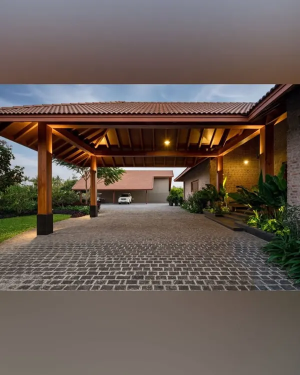 I designed this covered driveway with a warm, wooden structure and cobblestone path to create a grand yet welcoming arrival experience. The strategic landscape lighting highlights the architectural details and surrounding greenery, ensuring the entrance is impressive day and night.