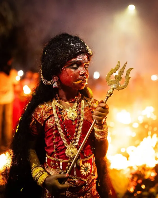 A young devotee embodying the spirit of goddess Kali during the Kulasai Dasara festival. This portrait, illuminated by the surrounding fires, captures the profound intersection of childhood innocence and ancient tradition in a single, powerful moment.