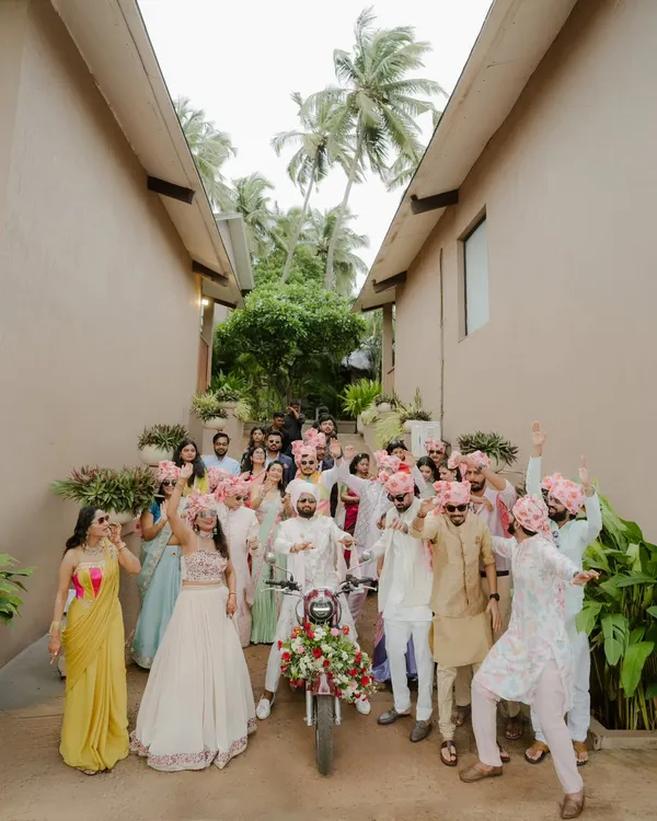 The groom's grand Baraat entry on a decorated Bullet, surrounded by his cheering friends and family. This shot is all about capturing the high energy, swagger, and celebratory chaos of the groom's procession.