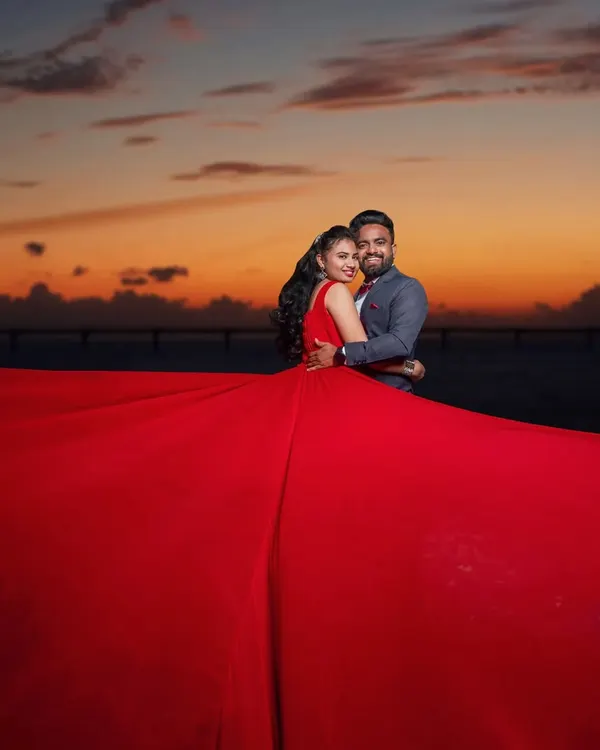 This stunning red gown with a dramatic, flowing tail is perfect for making a statement in your pre-wedding photoshoot. It's available for rent and comes with optional sleeves for a different look.
