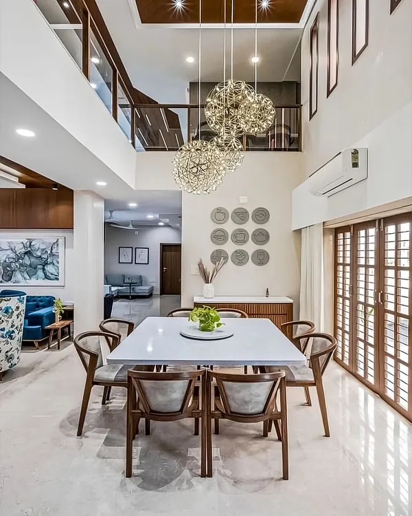 A bright and airy dining space in a double-height room. The modern wooden dining set is beautifully illuminated by a cluster of stunning spherical chandeliers.