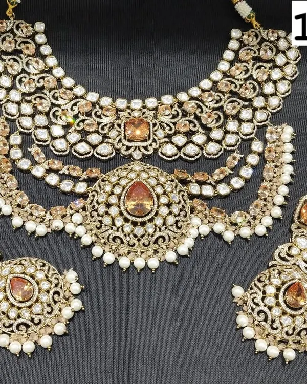 A magnificent bridal choker set made with uncut kundan and polki stones, featuring warm, amber-colored center stones. The set includes a multi-layered necklace, matching earrings, and a maang tikka.
