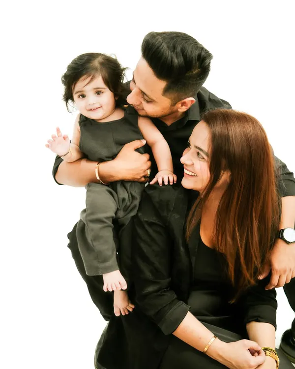 A beautiful family portrait. Coordinating in black outfits, this family of three shares a moment of love and happiness. The baby's wave is a perfect touch.