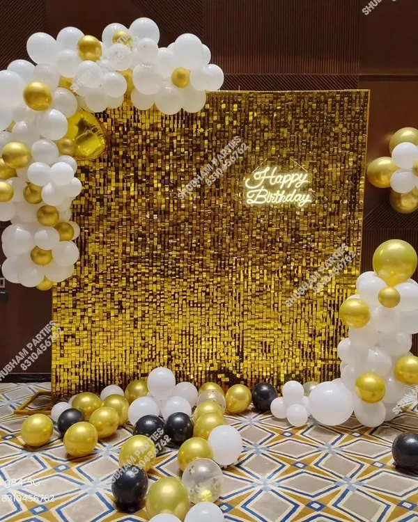 A stunning gold sequin wall backdrop, perfect for adding glamour to any birthday party. This setup includes a white and gold balloon garland and a "Happy Birthday" neon sign.