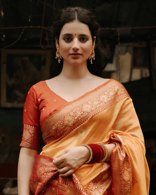 A portrait that captures timeless grace. The model, draped in a beautiful Banarasi saree, looks on with a serene expression, her elegance enhanced by the rustic market setting.