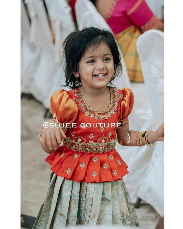 This is the beautiful Kanvi, smiling brightly in her custom-designed outfit. I created this special peplum blouse with traditional puff sleeves and intricate zardozi embroidery around the neckline and waist. It’s paired with a light, pleated lehenga skirt, making it perfect for her to run and play comfortably during any celebration.