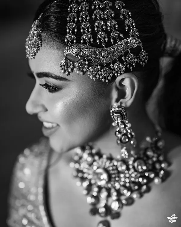 A timeless black and white close-up of the bride, highlighting her intricate jewelry and joyful smile. This classic style emphasizes emotion and detail.
