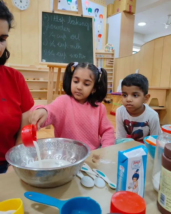 Baking a cake is a lesson in so many things. Here, a child carefully measures milk, learning about quantities and the importance of following a recipe.