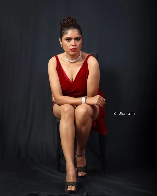 A full-length studio shot in a red dress against a dark backdrop. The lighting is set up to create a bold, confident mood for a modern portfolio.