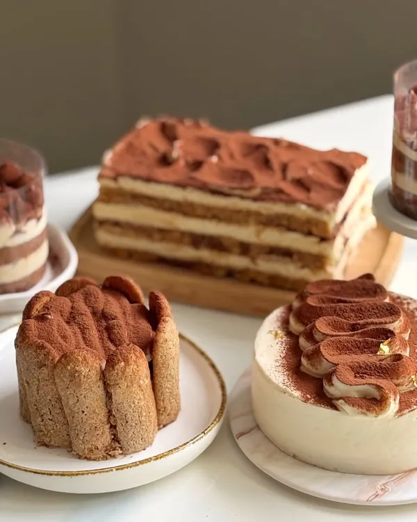A beautiful spread of the different Tiramisu styles I teach in my eggless workshop. From a classic layered cake and a Charlotte-style presentation to elegant single-serving cups, you'll learn it all.