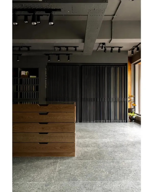 The interior of the boutique veneer showroom we designed in Bangalore. The space uses an earthy, moody palette with industrial elements like exposed track lighting and concrete floors to create a sophisticated backdrop for the wood products.