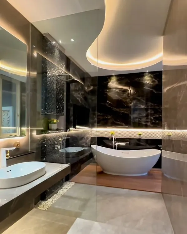 This master bathroom exemplifies our approach to creating a personal sanctuary. We used large format black marble slabs to create a glorious, seamless wall, juxtaposed with the warmth of a wooden platform for the freestanding tub. The custom-designed ceiling cove and backlit mirror provide layered, ambient lighting that enhances the mood while ensuring functional clarity.