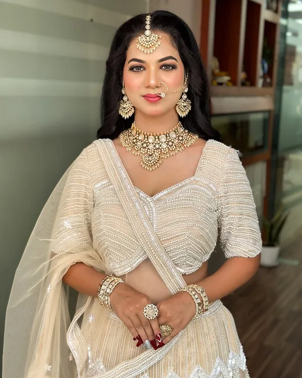 A stunning reception look in a white lehenga. The makeup is soft yet glamorous, with a focus on glowing skin and defined eyes.