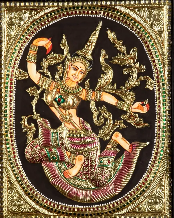 A detailed photograph of a traditional, ornate Tanjore painting depicting a celestial dancer, capturing the gold foil and embedded gems.