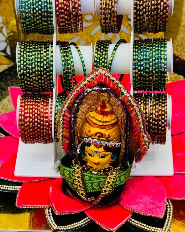 A beautiful bangle platter for a Gowri pooja or half-saree function. The goddess idol is placed in the center of a lotus-shaped base, surrounded by colorful glass bangles.