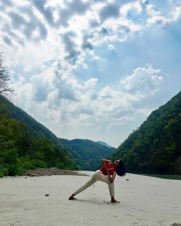 Practicing Parivrtta Parsvakonasana, or Revolved Side Angle Pose, by the Ganga. This twisting pose detoxifies the body and improves spinal mobility, and the natural setting amplifies the feeling of renewal.