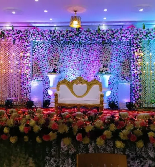 A full-coverage floral wall reception stage, combining thousands of flowers with strategic uplighting to create a breathtaking and luxurious backdrop for the couple.