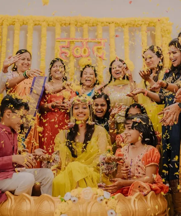A joyous Haldi celebration! The bride is surrounded by her family as they shower her with flower petals in a moment of pure happiness.