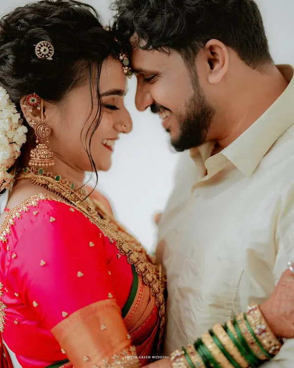 A moment of pure connection, as the bride and groom touch foreheads in a gesture of love and unity. The vibrant colors of their attire and their joyful smiles make this a quintessential wedding portrait.