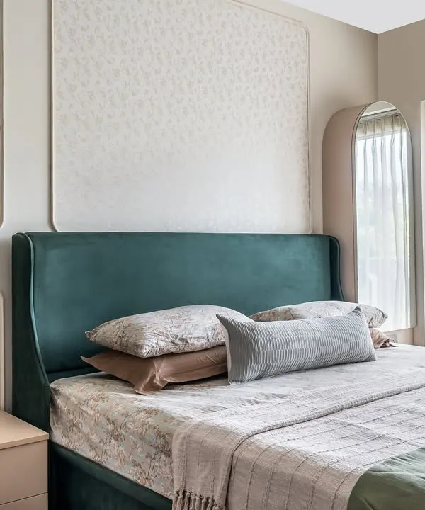 The master suite in 'The Flux Abode' features an emerald green bed set against an ivory wall with floral wallpaper inlays. The design is a perfect blend of contemporary sophistication and subtle luxury.