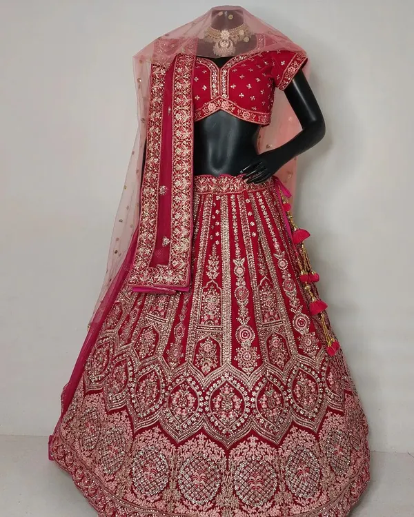 A beautiful red bridal lehenga with pink embroidery displayed on a mannequin. This piece offers a trendy yet elegant look, available for both rent and purchase.