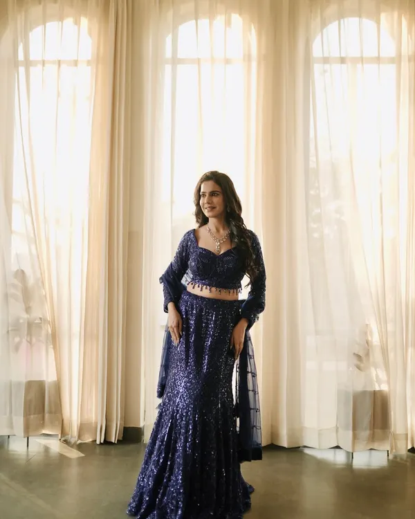 A full-length shot of a glamorous navy blue sequin lehenga. The indoor lighting and elegant backdrop make it perfect for a reception or cocktail party lookbook.