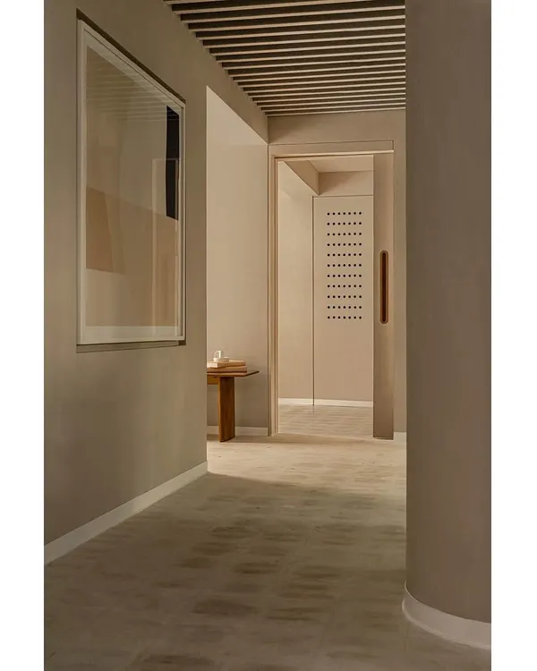 This corridor in the 'Crème' wellness center showcases our concept of creating a seamless, flowing space. The walls, floor, and even the curved column are finished in the same soft, creamy texture, creating a monolithic effect that is both calming and sophisticated.