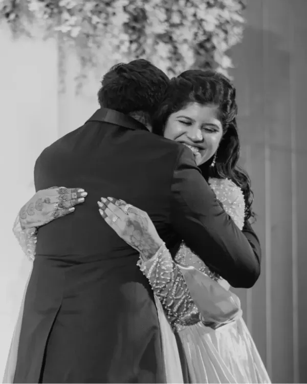 A powerful and emotional black and white photo of a bride sharing a tight hug, capturing a moment of overwhelming love and joy.