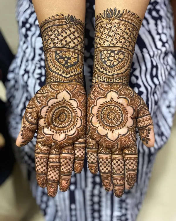 A full-coverage design featuring a large floral mandala on the palm and intricate jaali (net) patterns on the wrist cuffs. This is a classic bridal look that feels both traditional and timeless.
