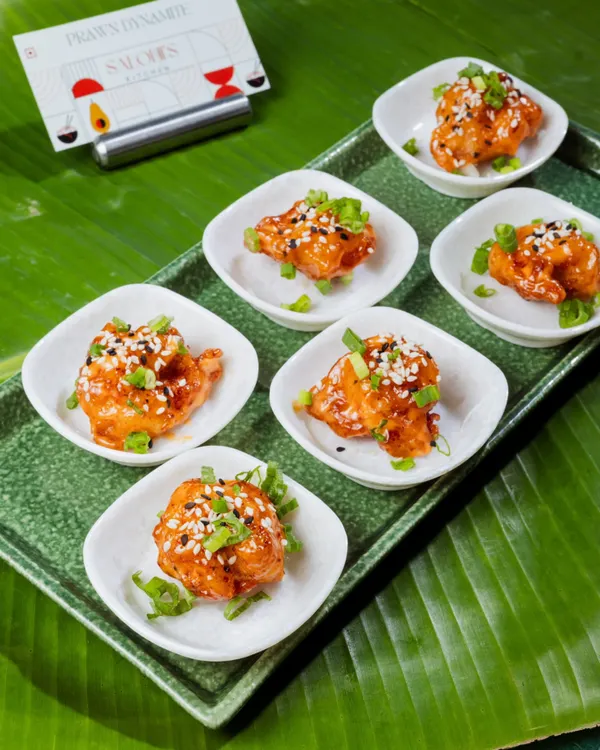 These are my Prawn Dynamite appetizers, served in individual portions. The crispy prawns are tossed in a creamy, spicy sauce and garnished with sesame seeds and spring onions, making them an instant party favorite.