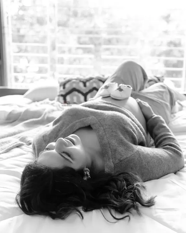 A quiet moment of bliss. This black and white lifestyle photo, with tiny baby shoes resting on the bump, captures the peaceful anticipation of waiting for your little one at home.