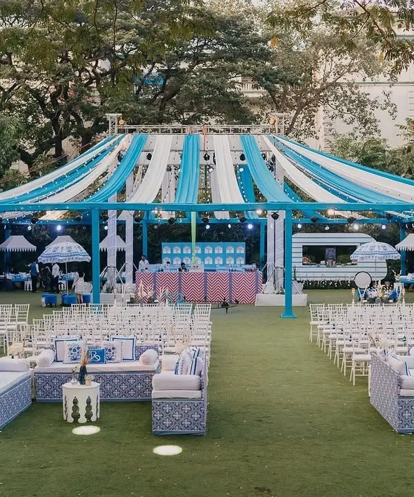 A wide view of the 'Bar Palladio' inspired Haldi for Yasha and Rahil. The venue was transformed with a canopy of blue and white drapes, custom-printed lounge seating, and a fresh, non-traditional color palette.