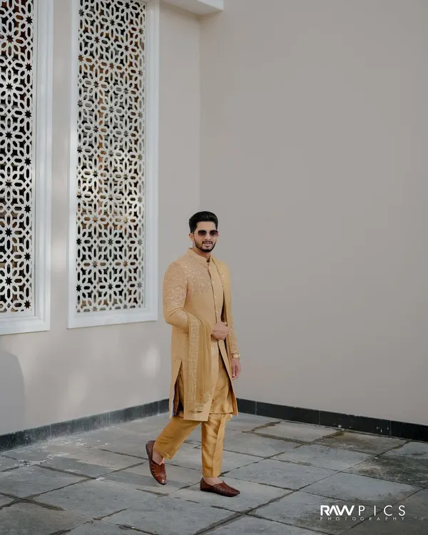 A stylish groom in a golden sherwani. This is a perfect look for a grand wedding or reception, captured beautifully here.